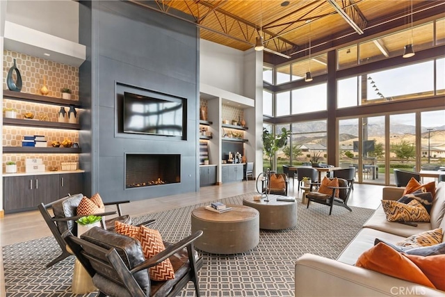 living room with a high ceiling, wood ceiling, a large fireplace, and built in shelves
