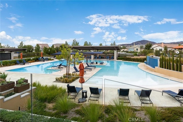 community pool with a mountain view, fence, and a patio