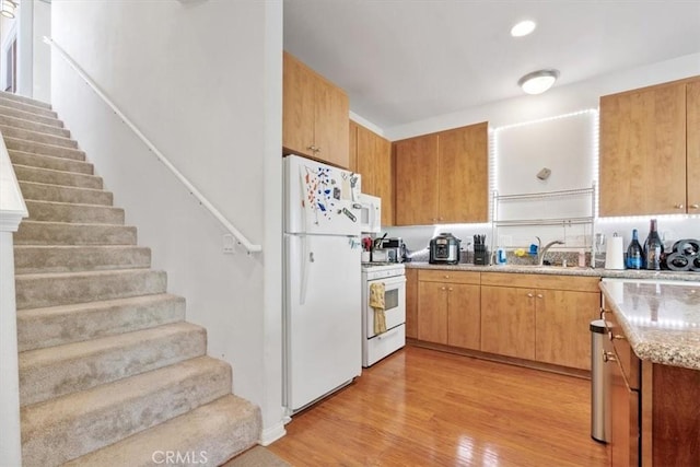 kitchen with recessed lighting, white appliances, a sink, light wood-style floors, and light stone countertops