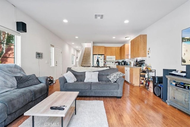 living area with stairs, light wood finished floors, visible vents, and recessed lighting