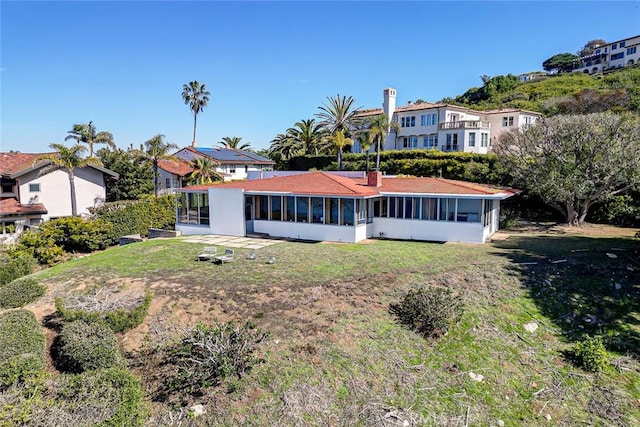 rear view of property with a yard, a residential view, and a sunroom