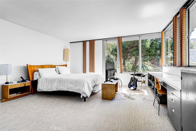 bedroom featuring light carpet and built in desk