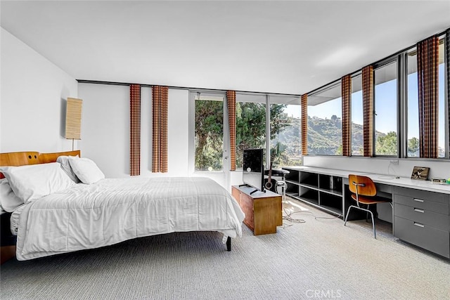 bedroom featuring light carpet, built in desk, and a mountain view