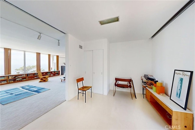 living area with light carpet, expansive windows, visible vents, and rail lighting