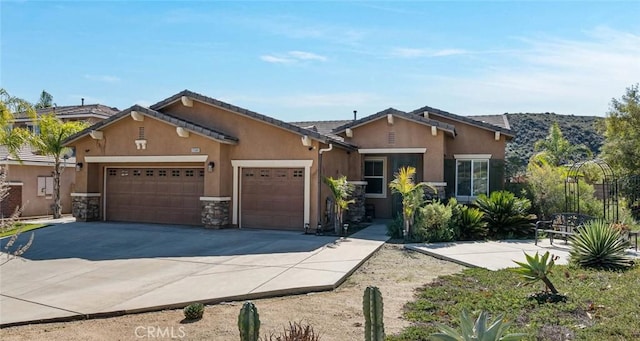 view of front of property with a garage, a tile roof, concrete driveway, stone siding, and stucco siding