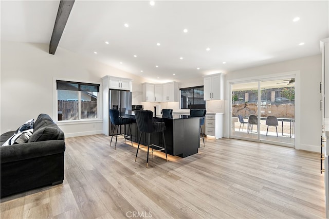 living area featuring lofted ceiling with beams, recessed lighting, light wood-type flooring, and baseboards