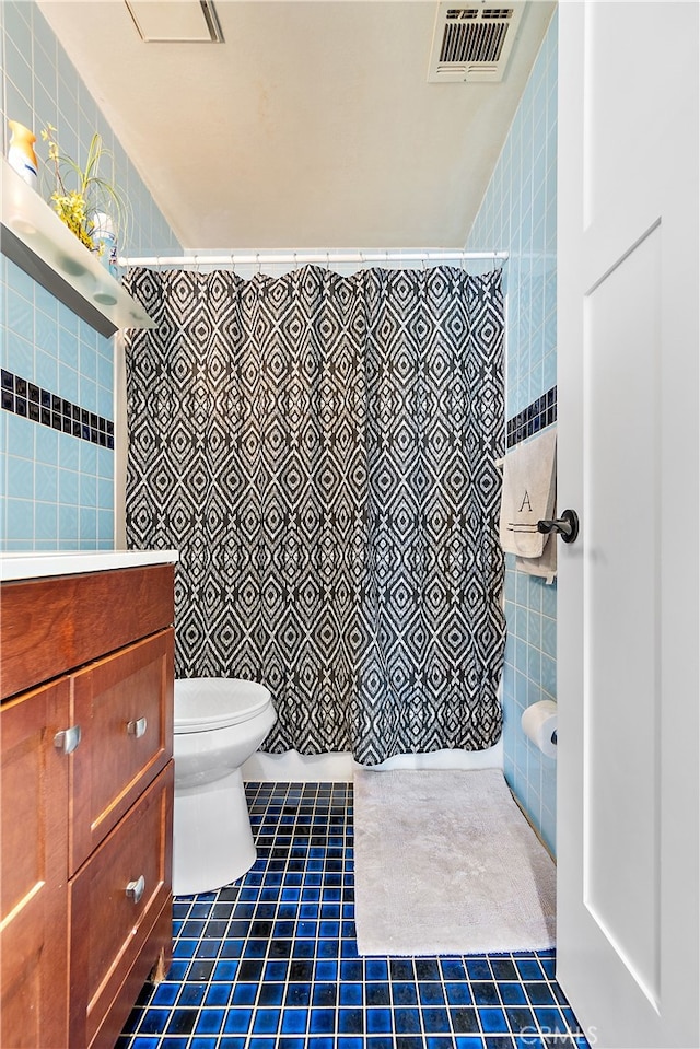 bathroom with tile patterned flooring, visible vents, tile walls, and toilet