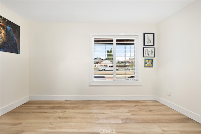 empty room featuring light wood finished floors and baseboards