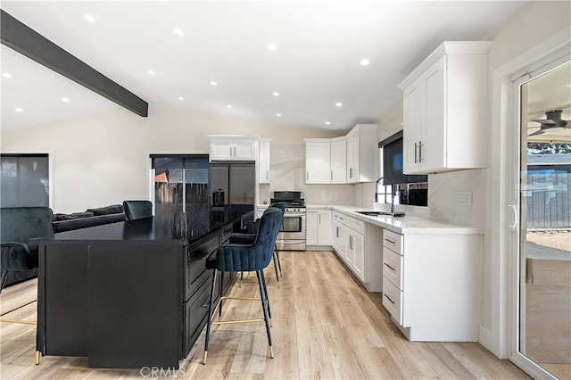 kitchen featuring a kitchen bar, white cabinetry, stainless steel appliances, and a sink