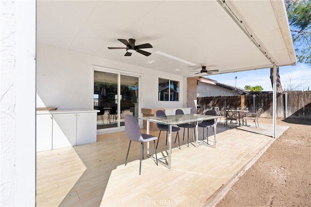 view of patio / terrace with ceiling fan, outdoor dining space, and fence