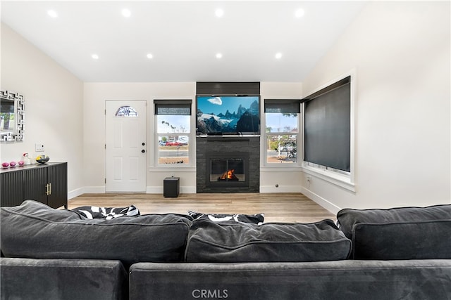 living area featuring light wood finished floors, a fireplace, baseboards, and vaulted ceiling