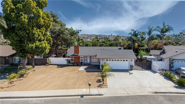 single story home featuring an attached garage, a chimney, fence, and concrete driveway