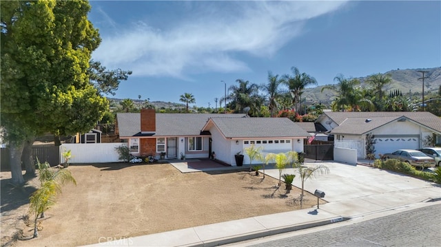 ranch-style home featuring a garage, fence, a mountain view, and concrete driveway