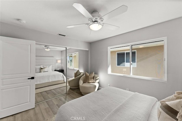 bedroom with light wood finished floors, ceiling fan, visible vents, and a closet