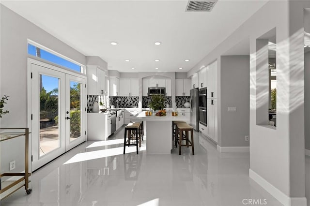 kitchen featuring a breakfast bar area, a kitchen island, visible vents, white cabinets, and appliances with stainless steel finishes