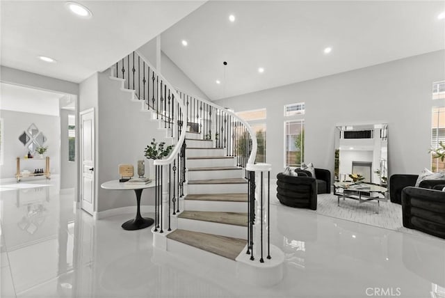 staircase featuring baseboards, high vaulted ceiling, and recessed lighting