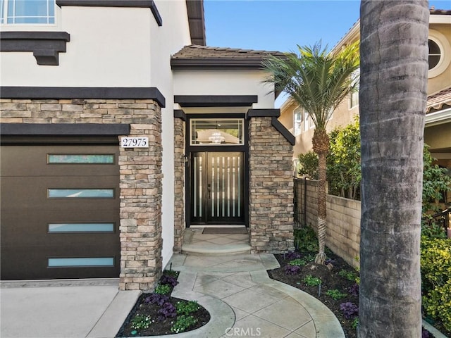 view of exterior entry featuring stone siding, fence, and stucco siding