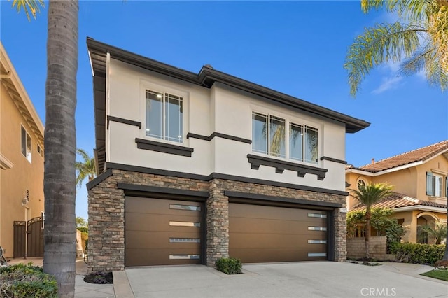 view of front of home with a garage, concrete driveway, stone siding, and stucco siding