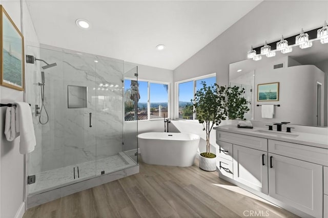 bathroom featuring a marble finish shower, lofted ceiling, visible vents, vanity, and wood finished floors