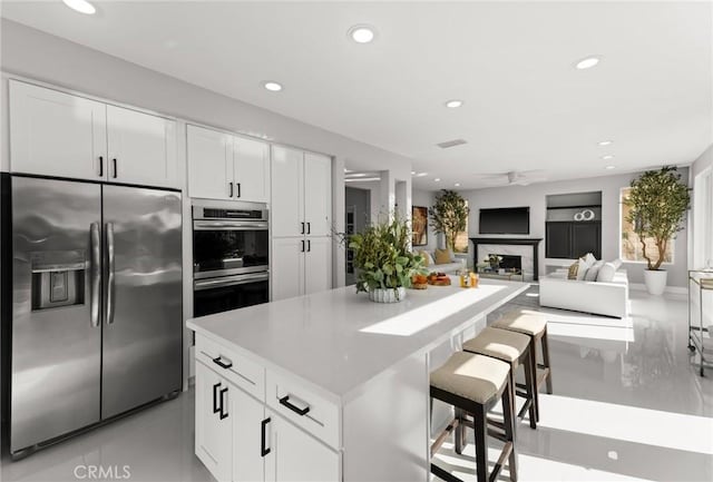 kitchen featuring a breakfast bar, appliances with stainless steel finishes, white cabinets, and open floor plan