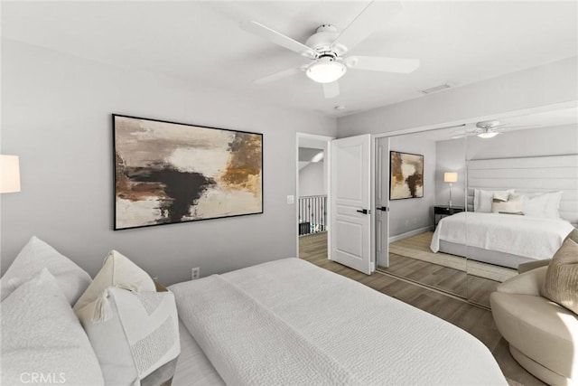 bedroom featuring baseboards, wood finished floors, visible vents, and a ceiling fan