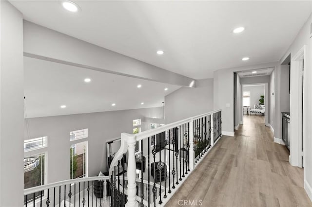 hall featuring recessed lighting, an upstairs landing, baseboards, vaulted ceiling, and light wood-type flooring