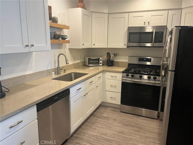 kitchen with appliances with stainless steel finishes, a sink, and white cabinets