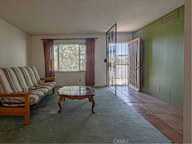 carpeted living room with a textured ceiling, tile patterned flooring, and visible vents