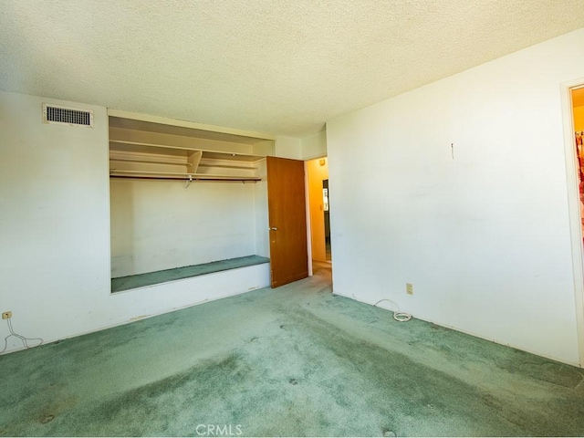 unfurnished bedroom featuring light carpet, a closet, visible vents, and a textured ceiling