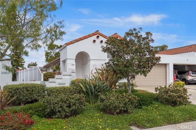 mediterranean / spanish house featuring a tile roof, stucco siding, concrete driveway, and a garage