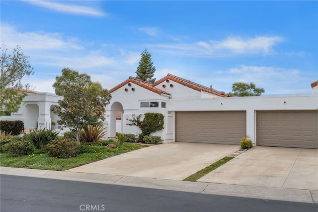 mediterranean / spanish home featuring stucco siding, concrete driveway, and an attached garage