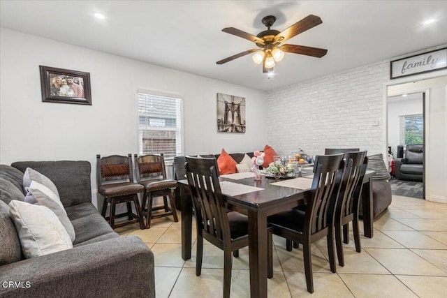 dining room with light tile patterned floors, brick wall, and ceiling fan