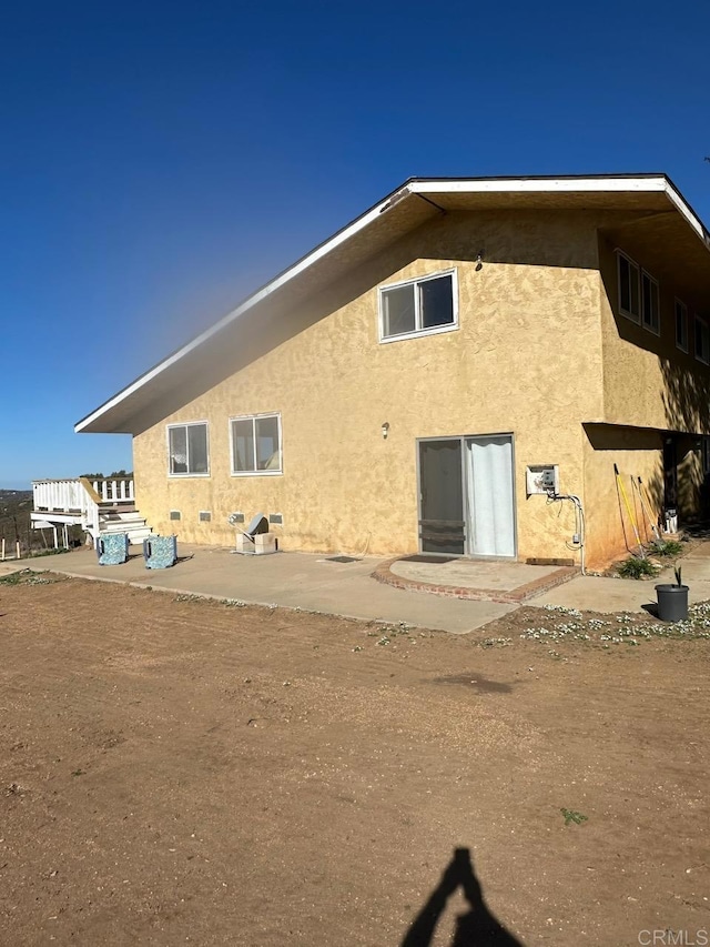 back of property with stucco siding and a patio