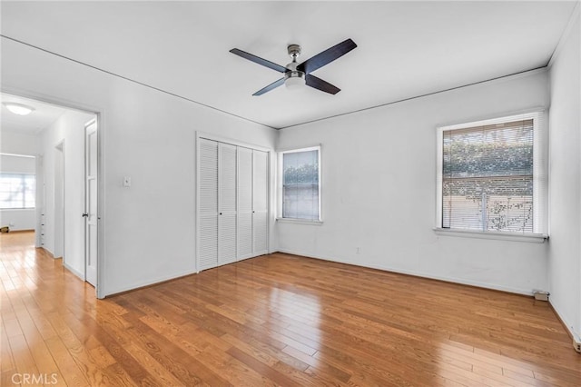 unfurnished bedroom featuring light wood-style floors, ceiling fan, baseboards, and a closet