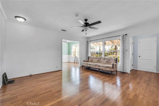 unfurnished living room featuring ceiling fan, visible vents, crown molding, and wood finished floors