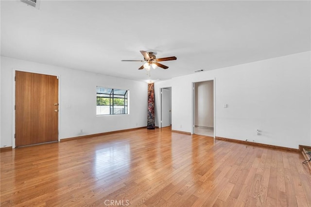 empty room featuring a ceiling fan, visible vents, light wood-style flooring, and baseboards