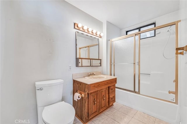 bathroom with combined bath / shower with glass door, vanity, toilet, and tile patterned floors