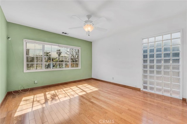 empty room featuring light wood finished floors, baseboards, visible vents, and a ceiling fan