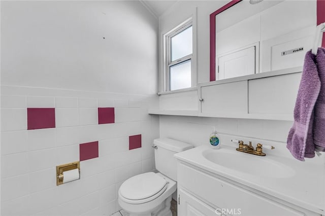 bathroom with vanity, toilet, and tile walls