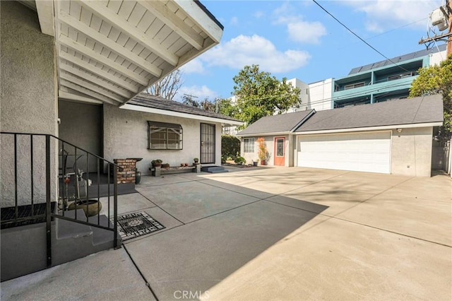 view of side of property featuring a garage, a shingled roof, and stucco siding