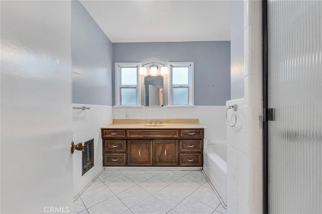 bathroom with wainscoting, a shower with shower door, tile patterned flooring, vanity, and tile walls