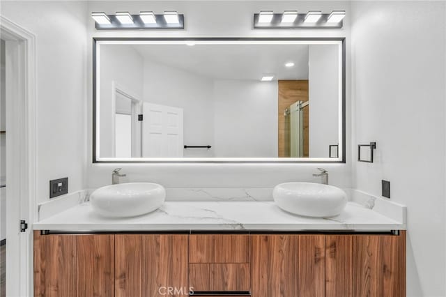 bathroom with double vanity, a shower stall, and a sink