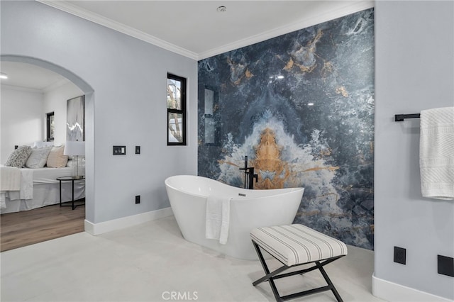 ensuite bathroom featuring baseboards, ornamental molding, a freestanding tub, and connected bathroom