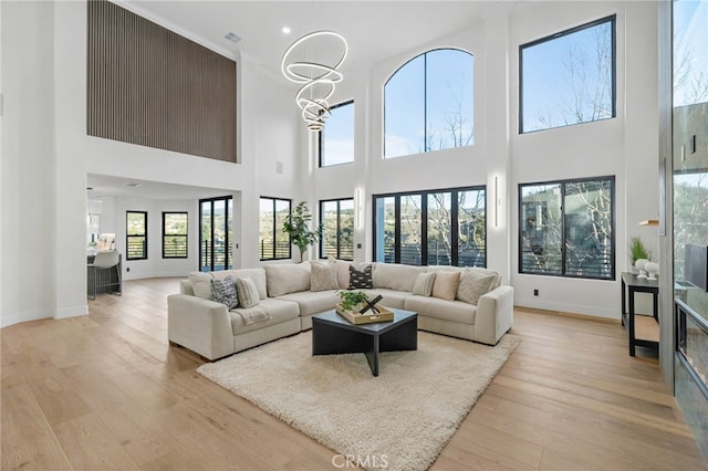 living room with light wood-style floors, baseboards, and an inviting chandelier