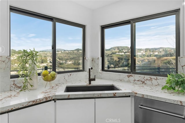 kitchen featuring a mountain view, white cabinets, and a sink