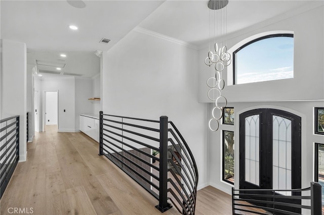 foyer featuring french doors, light wood finished floors, visible vents, ornamental molding, and baseboards