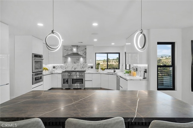 kitchen with wall chimney exhaust hood, modern cabinets, appliances with stainless steel finishes, and white cabinets