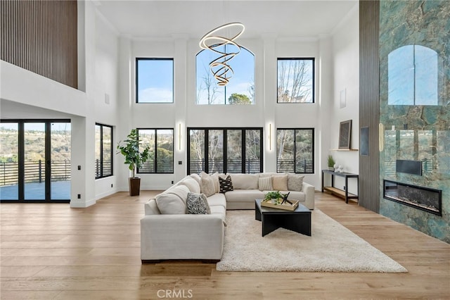 living area featuring a healthy amount of sunlight, light wood-style floors, a fireplace, and ornamental molding