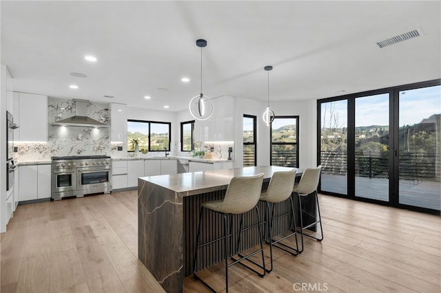 kitchen featuring visible vents, white cabinetry, appliances with stainless steel finishes, wall chimney exhaust hood, and modern cabinets