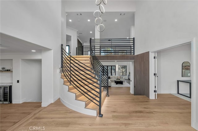 staircase featuring wine cooler, recessed lighting, baseboards, and wood finished floors